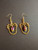Hanging gold coloring earrings with purple drop