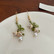 Kauniit helmiäishohtoiset roikkuvat korvakorut kellomaisilla kukilla (lyhyemmät)